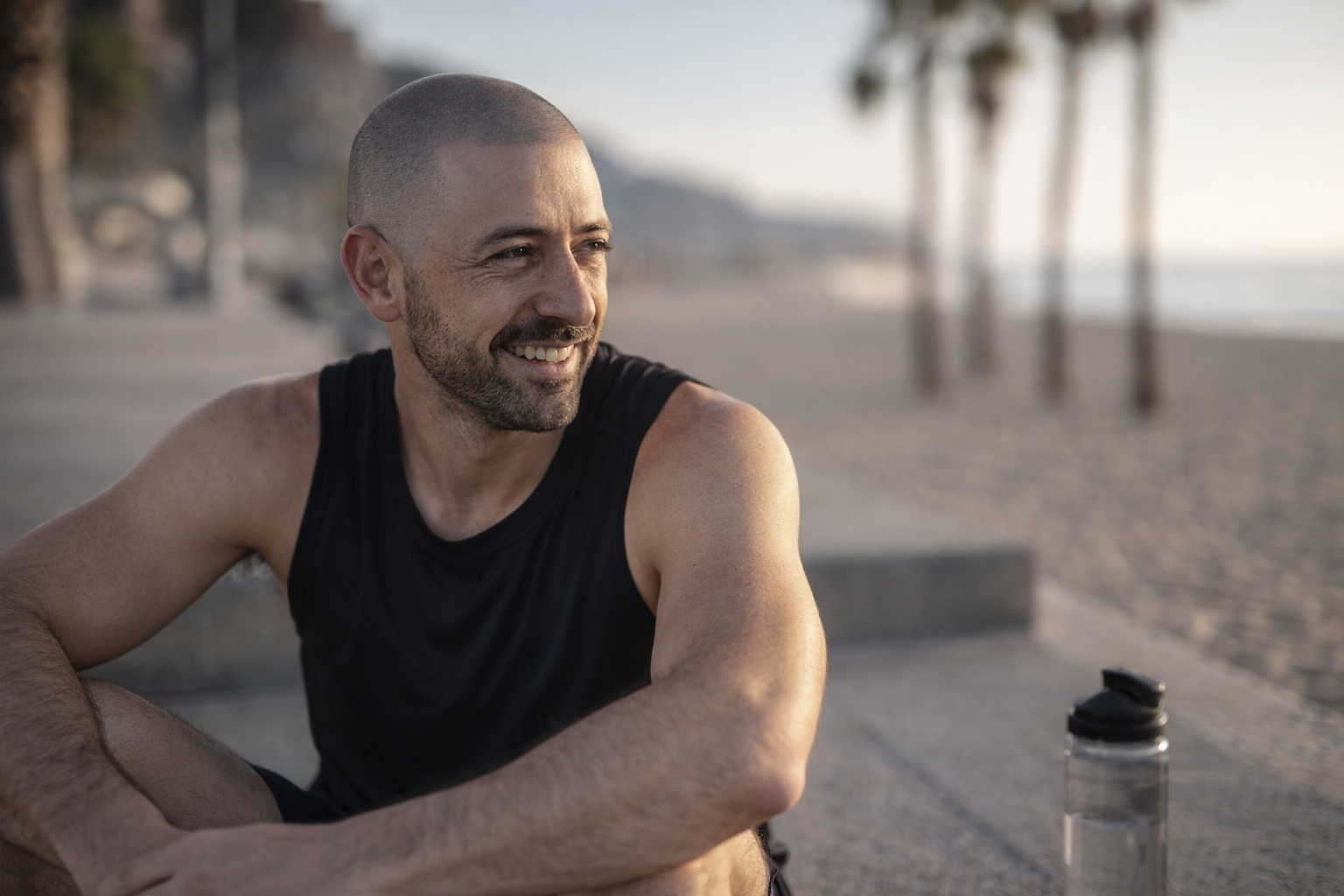 Man looking happy and confident after getting scalp micropigmentation (SMP) hair tattoo at the beach